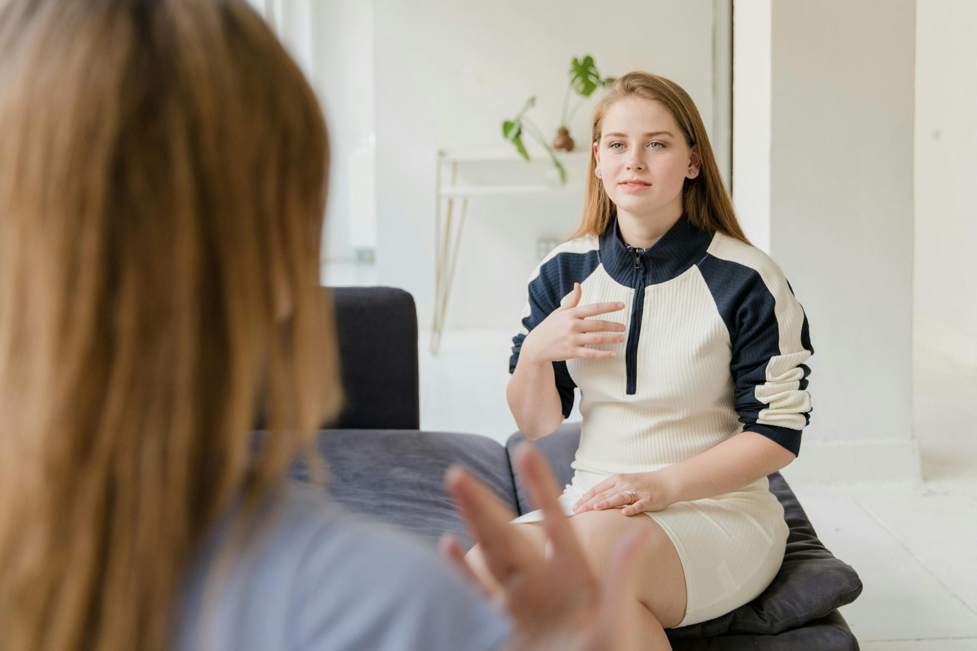Frauen unterhalten sich zu Hause auf einem Sofa in einem hellen Wohnzimmer.