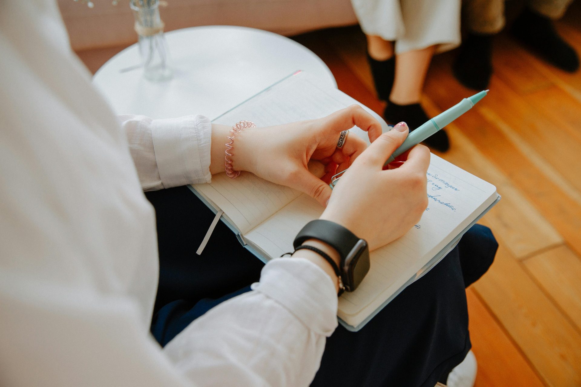 Nahaufnahme einer Person, die während einer Therapiesitzung Notizen macht; der Fokus liegt dabei auf der psychischen Gesundheit.