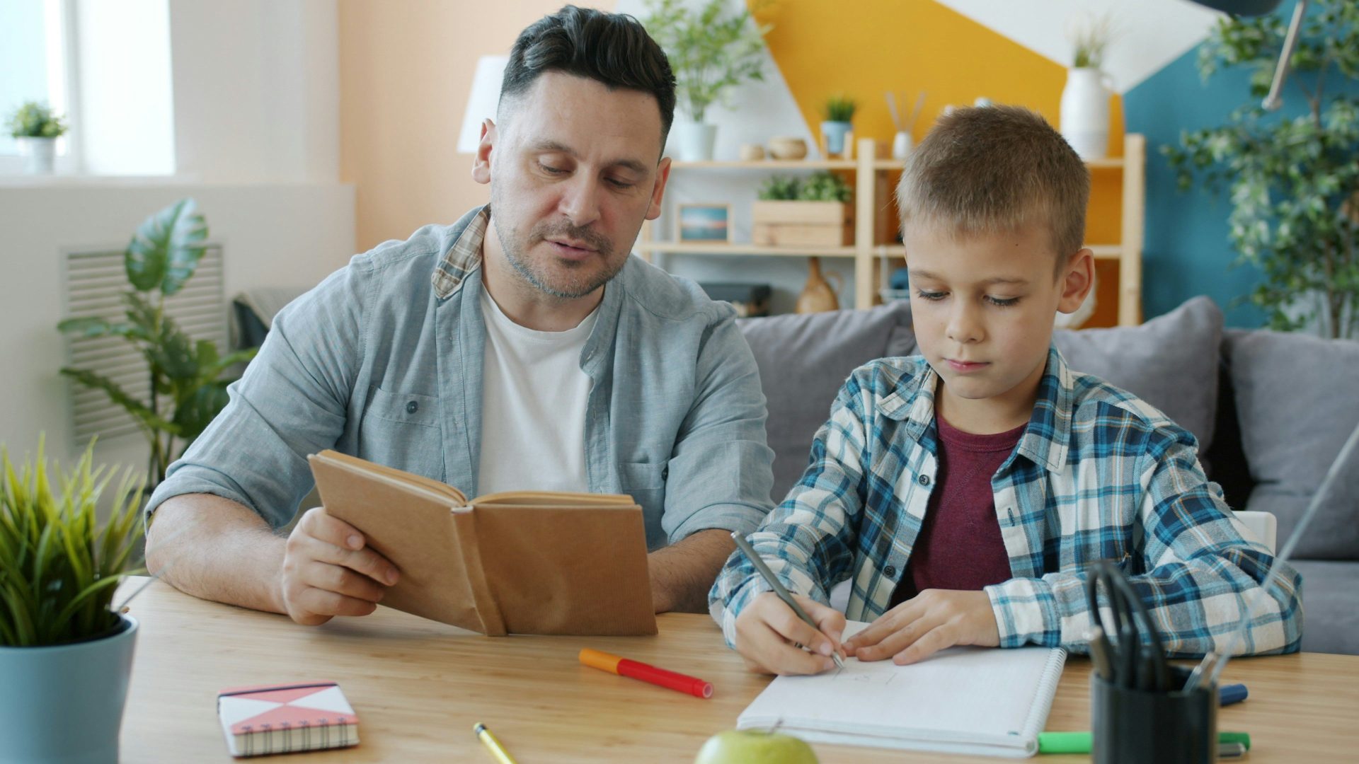 Vater und Sohn lesen und schreiben am Tisch
