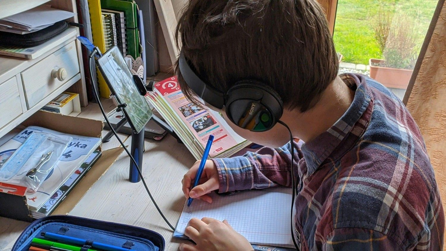 Ein junger Junge macht sich während des Online-Unterrichts zu Hause Notizen und konzentriert sich aufs Lernen.